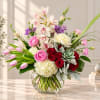 Mixed bouquet of orchids, roses, tulips, and chrysanthemums in a glass vase