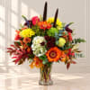 Mixed bouquet in a clear glass vase with orange, yellow, red, and white blooms