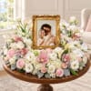 Floral arrangement around a gold photo frame on a round table