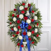 Standing funeral wreath with red and white flowers and a blue ribbon