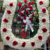 Heart-shaped white floral wreath with red roses and a white ribbon bow