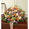 Large floral casket spray with orange, pink, white, and purple blooms
