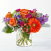 Orange and purple mixed bouquet in a clear glass vase