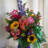 Mixed bouquet in a purple vase with sunflowers, roses, and purple spikes