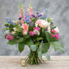 Mixed bouquet of pink, white, and blue flowers in a glass vase