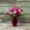 Pink and purple mixed bouquet in a magenta glass vase