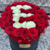 Red and white roses arranged in a round black box