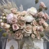 Blush and white rose arrangement above decorated white Bibles and a candle