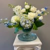White and blue floral arrangement in a blue glass vase