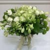 Green and white bouquet in a glass vase with ribbon