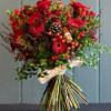 Bouquet of red flowers with berries and pinecones tied with a ribbon
