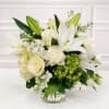 White lilies and cream roses arranged in a clear glass vase