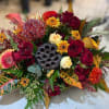 Mixed bouquet with red roses, yellow daisies, and tropical foliage