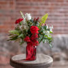 Red and white floral arrangement in a red glass vase with a ribbon