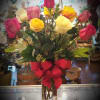 Bouquet of multicolored roses in a clear glass vase with a red bow