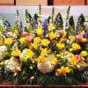 Large altar flower arrangement with yellow lilies and roses, white hydrangeas, pink roses, and blue delphinium.