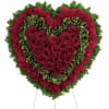 Heart-shaped floral tribute with red roses and carnations on a stand