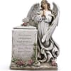 Angel statue beside a memorial stone with small pink roses