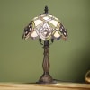 A domed stained-glass table lamp with cream, green, and amber tones brings