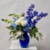 White roses and blue flowers in a cobalt vase