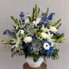 Blue and white floral arrangement in a white vase with lilies and roses