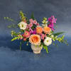 Mixed bouquet of peach, white, and pink flowers in a white vase