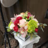 Bouquet of pink and red roses with orchids and green blooms in a white vase