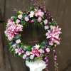 Circular floral wreath with pink lilies and lavender roses on a stand