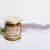 Amber jar soy candle with gold lid beside lavender sprigs on a light surface