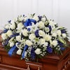 White and blue floral arrangement on a wooden casket