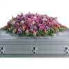 Pink and purple floral casket spray on a gray casket