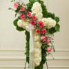 Standing floral cross with pink roses and white flowers on an easel