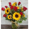 Bouquet of red roses and yellow sunflowers in a glass vase