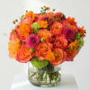 Orange and pink flower bouquet in a clear glass vase