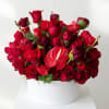 Red rose arrangement in a white round box with an anthurium bloom