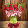 Bouquet of red tulips and pink orchids in a glass vase with a red bow