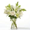 White lilies and roses arranged in a clear glass vase