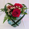 Red roses with small white blossoms in a glass vase
