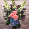 An artful arrangement of pink roses contrasted by vivid blue hydrangea and