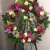 Large floral wreath on an easel with pink, yellow, and purple blooms
