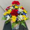 Colorful bouquet of red carnations, yellow daisies, and white flowers in a clear vase