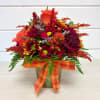 Autumn bouquet of red and orange flowers in a vase with plaid ribbon