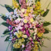 Large cascading bouquet of orchids, roses, and mums in pink, yellow, white, and purple