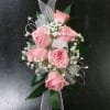 Pink rose corsage with baby's breath and silver ribbon on a dark background