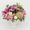 Pink and white mixed flower arrangement with lilies and roses in a white urn-style vase