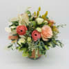 Peach and coral roses with white blooms arranged in a decorative ceramic pot.