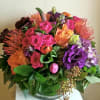 Colorful bouquet of roses, hydrangea, and tropical blooms in a glass vase