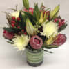 Bouquet of pink protea and white chrysanthemums in a striped glass vase