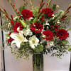 Red gerbera daisies and white lilies in a tall glass vase