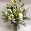Tall white floral arrangement in a glass vase with calla lilies and snapdragons